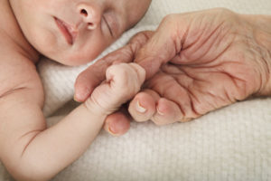 Elderly Lady's Hand Holding Baby's Hand